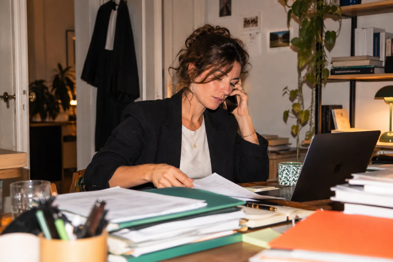 Une avocate au téléphone dans son cabinet, un dossier ouvert devant elle.